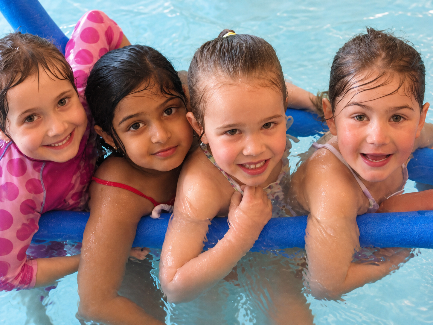 Four children holding a blue float together in the swimming pool